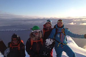 heliskiers on peak overlooking ocean